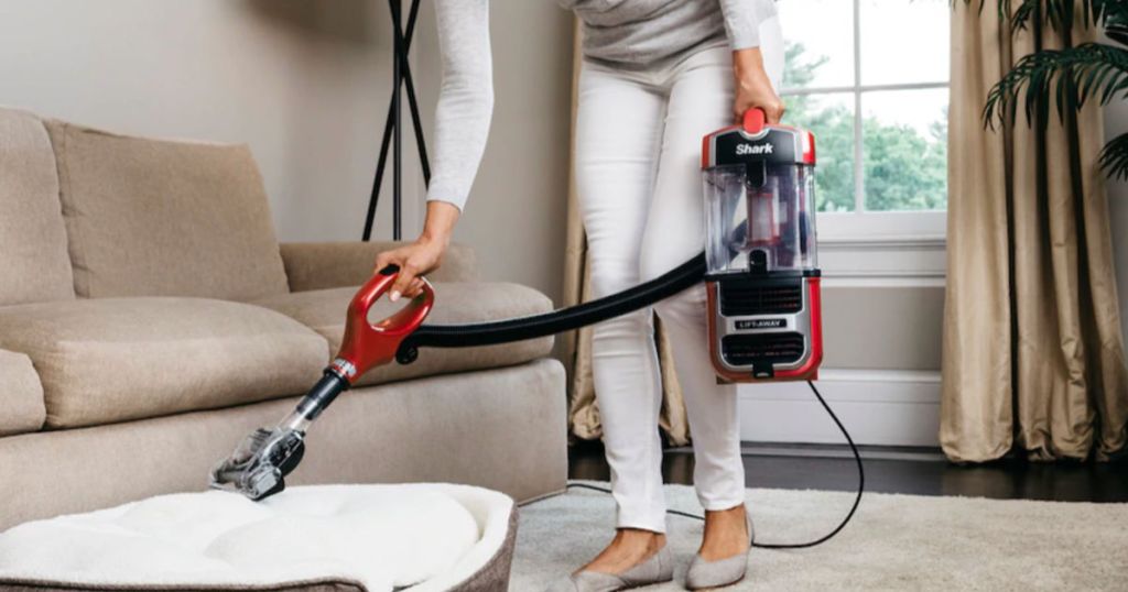 Woman using shark navigator lift away on dog bed