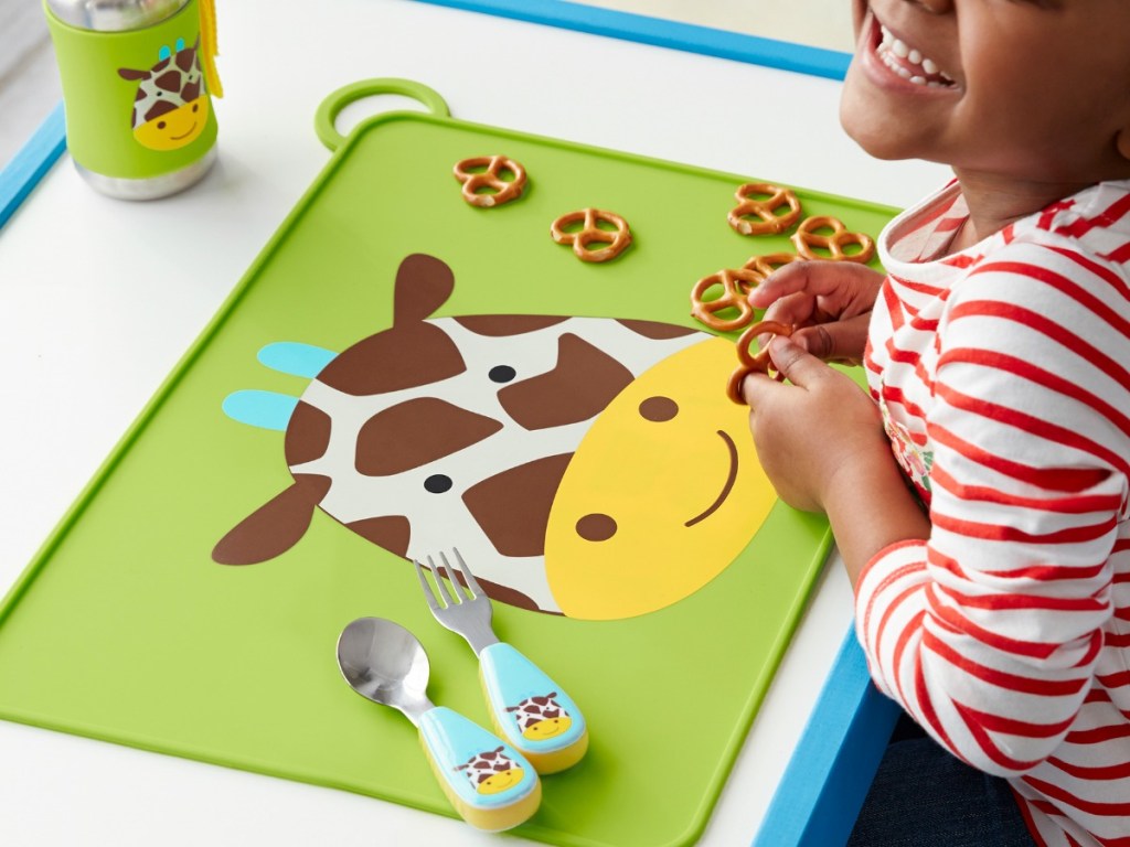 young girl eating snacks off Giraffe food mat