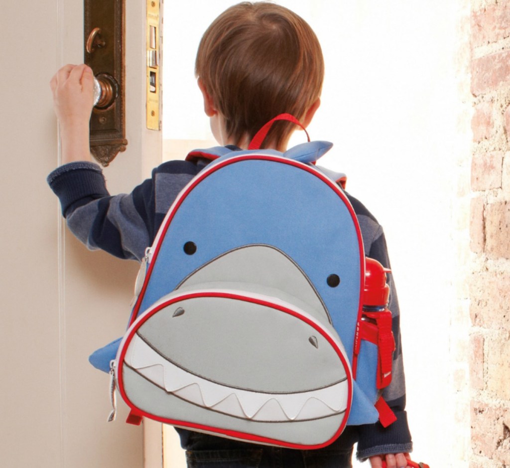 Little boy walking out the front door wearing a Sharked themed Skip Hop Zoo Backpack