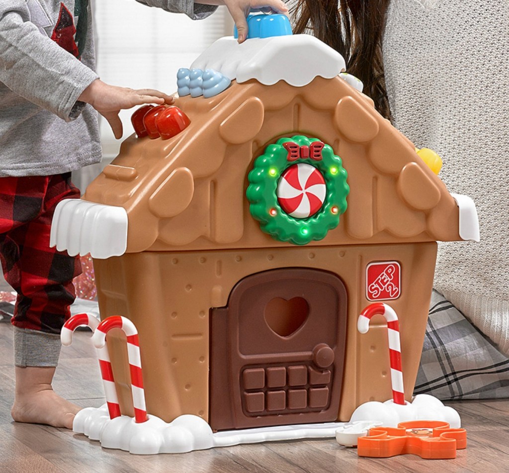 Mom and child playing with a gingerbread themed house