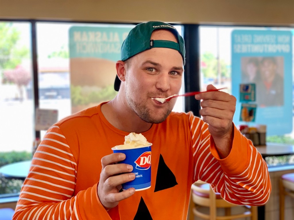 Man in pumpkin attire eating Pumpkin Pie Blizzard in Dairy Queen