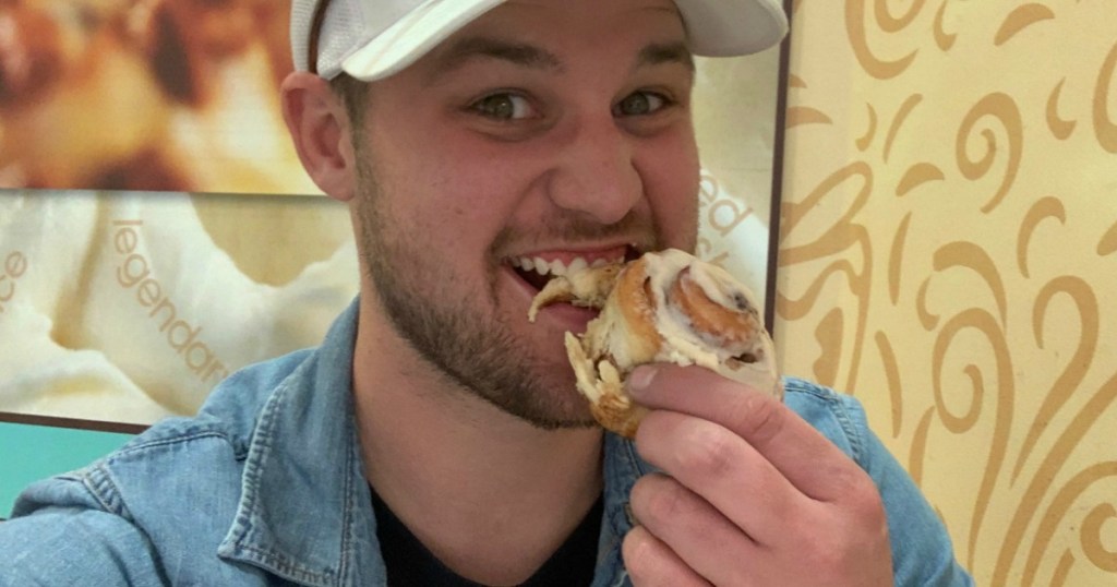 Man eating Cinnabon cinnamon roll in restaurant