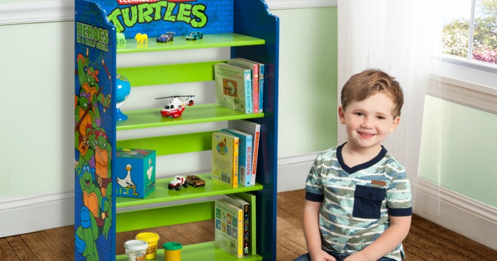 boy sitting next to a Teenage Mutant Ninja Turtles bookshelf