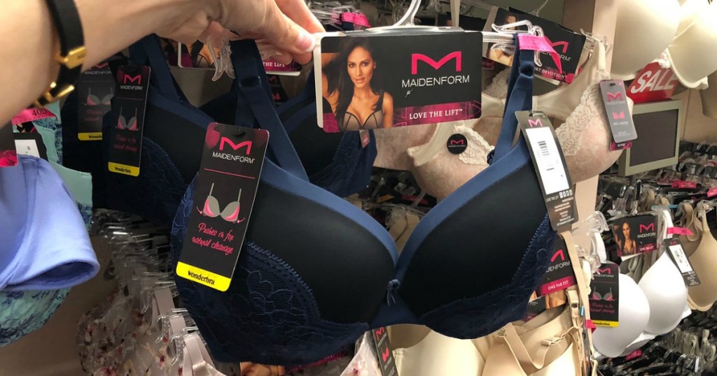 woman holding up Maidenform bra on hanger in store