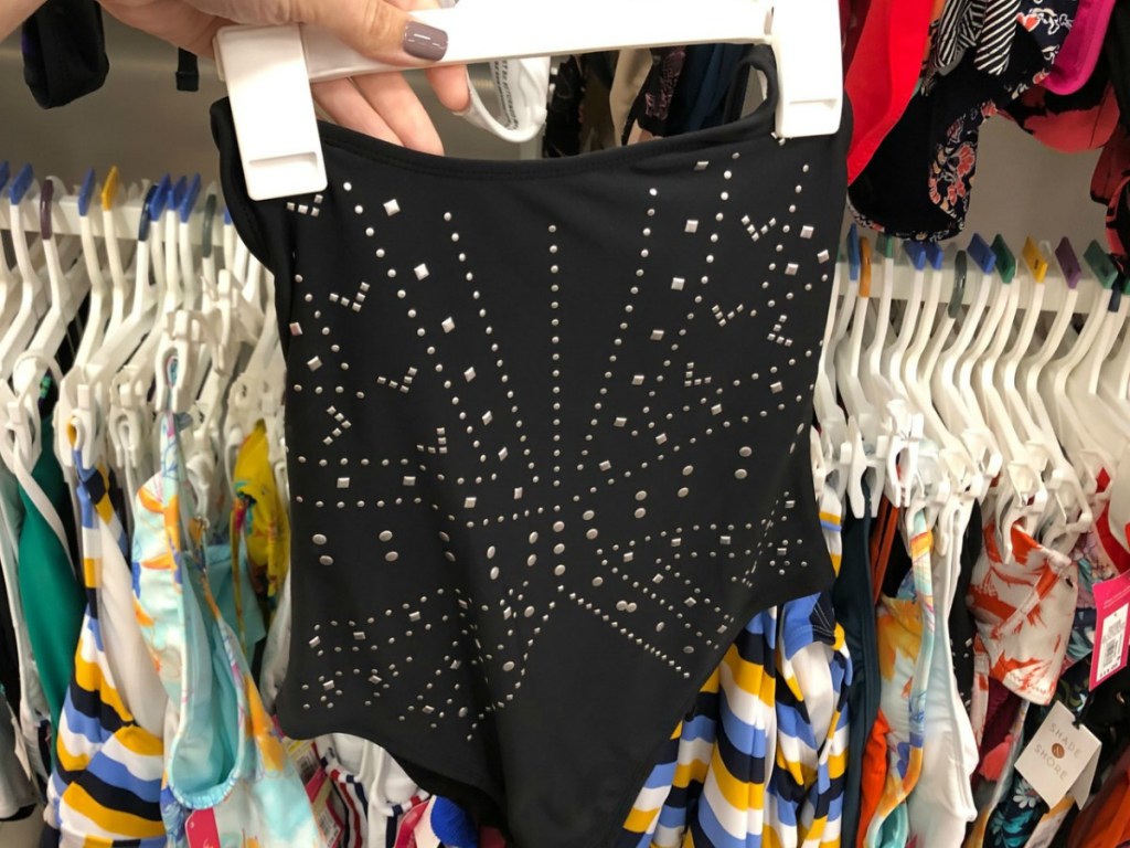 hand holding women's black swimsuit in store