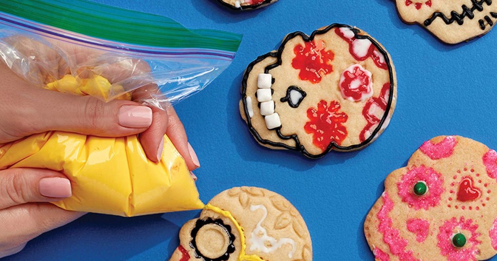 woman squeezing icing out of ziploc bag onto cookies