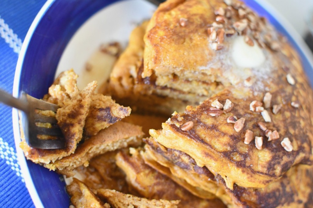 fork cutting into pumpkin pancakes with syrup