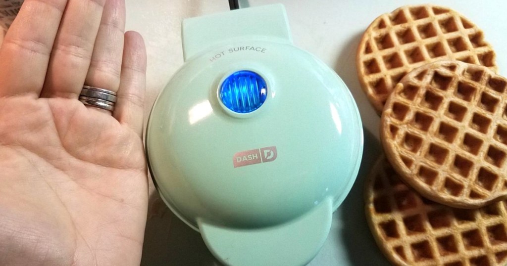 hand next to a dash dash mini waffle maker