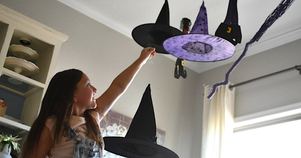 girl putting witch hats on ceiling to hang