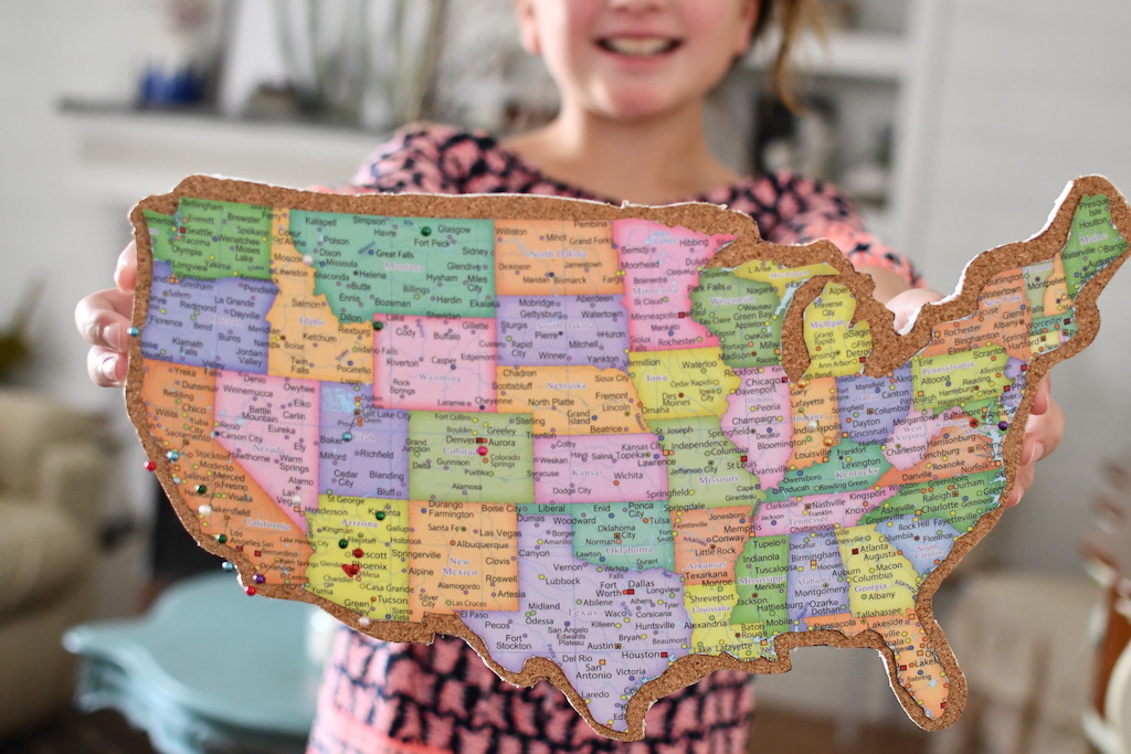 little girl smiling holding DIY travel map