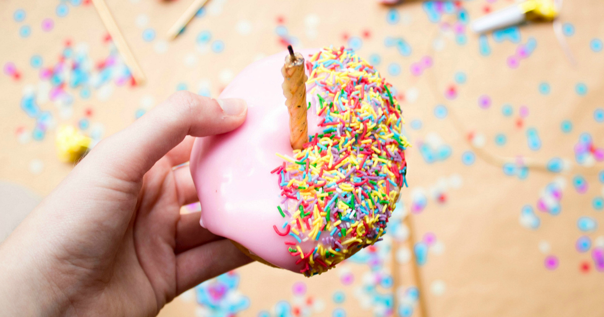 kid holding sprinkle donut with candle