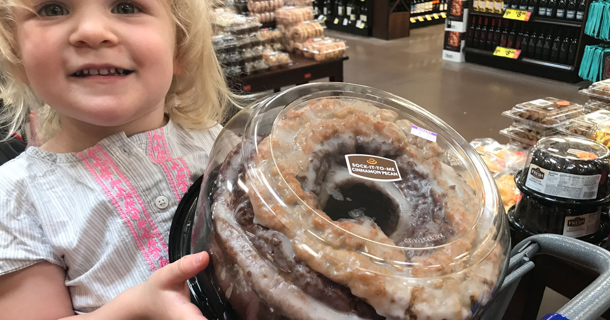 little girl in grocery shopping cart with cake