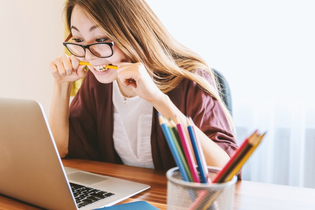 girl in front of laptop with pencil in mouth