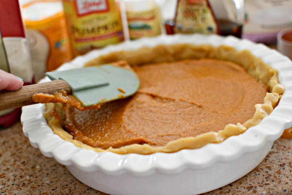 spreading a pumpkin pie before baking