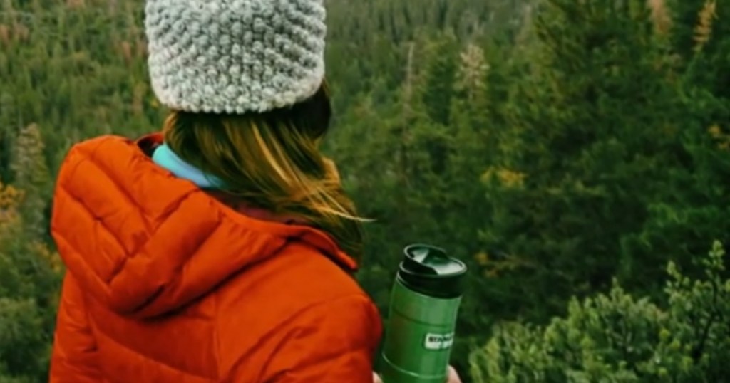 woman carrying stanley mug looking at trees