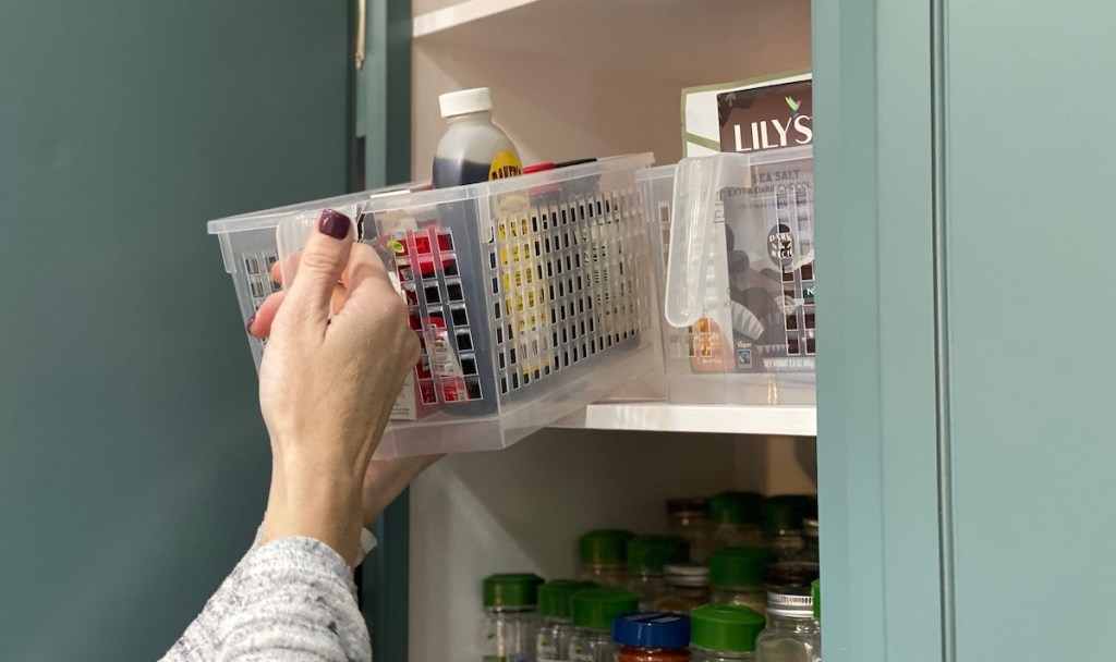 hand holding pulling out clear basket from cabinet