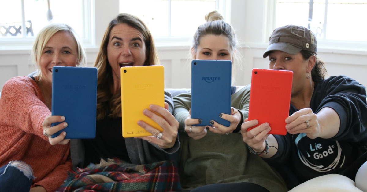 four women sitting together and holding up kindles