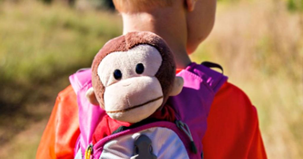 kid with curious george dog in backpack