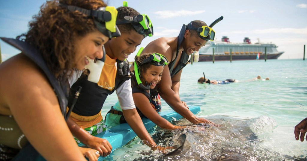 family in water with disney cruise in the back