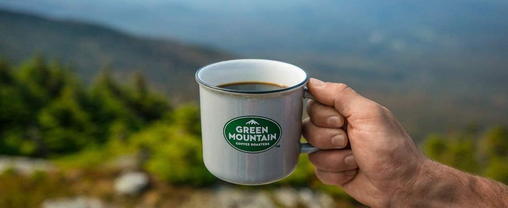 person holding green mountain coffee mug