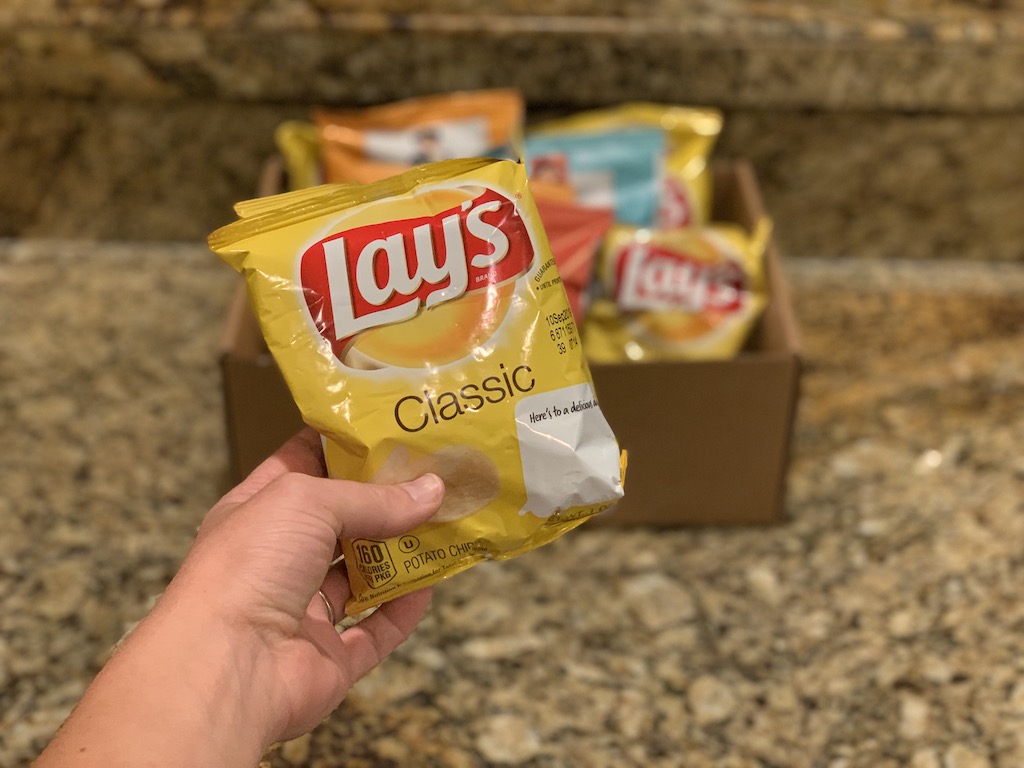 Hand holding up a bag of Lay's Classic Potato Chips