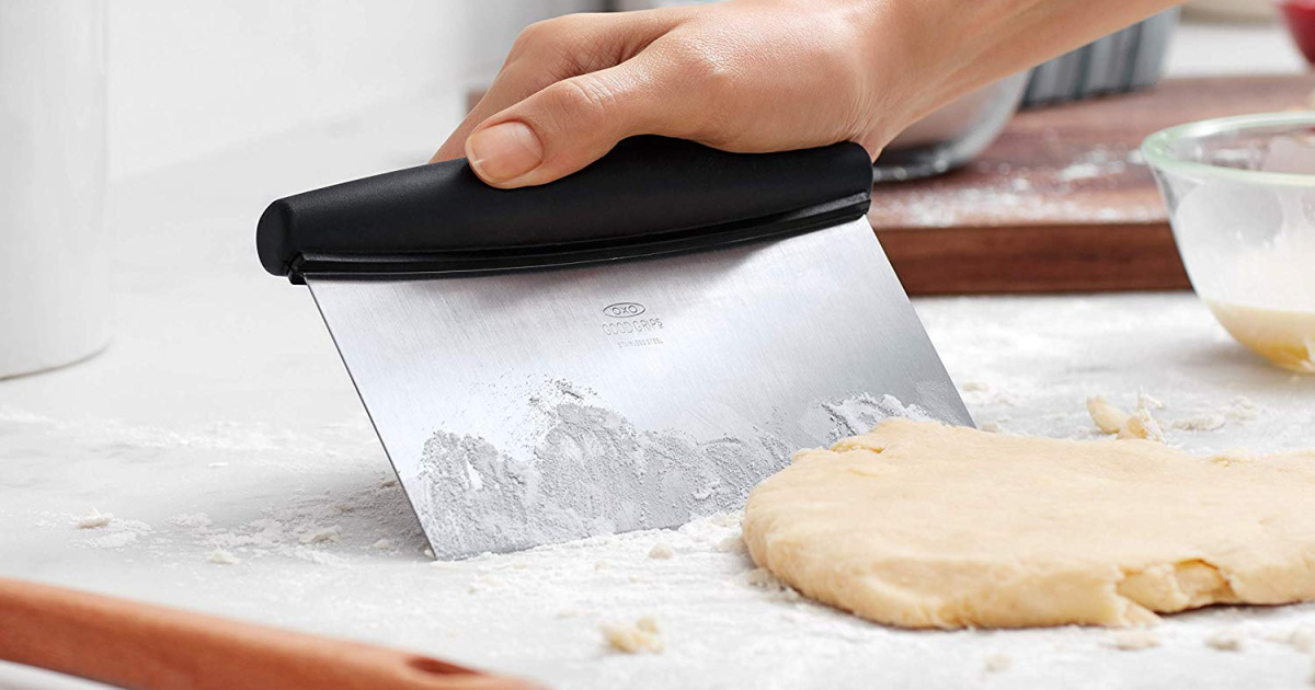 hand using an OXO Good Grips bench Scraper to lift pastry dough off a floured surface