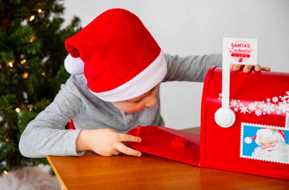 boy placing letter inside Santa's Enchanted Mailbox