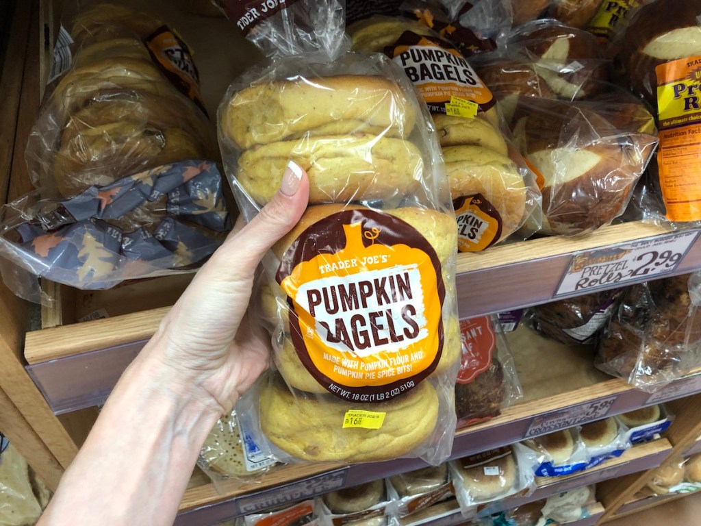 women's hand holding Trader Joe's pumpkin bagels in store