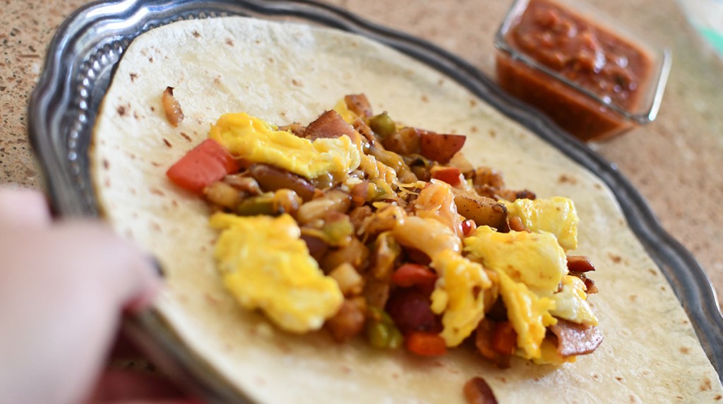 adding eggs and potatoes to tortillas