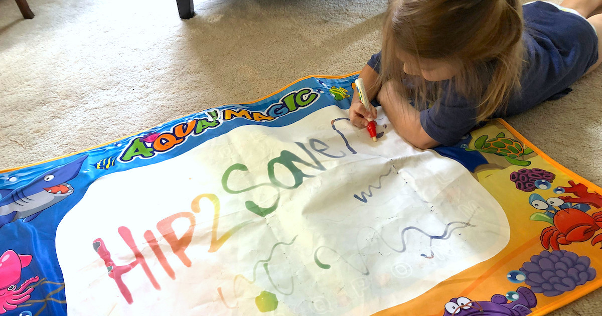 girl playing on aquadoodle mat on carpet - best toy deals