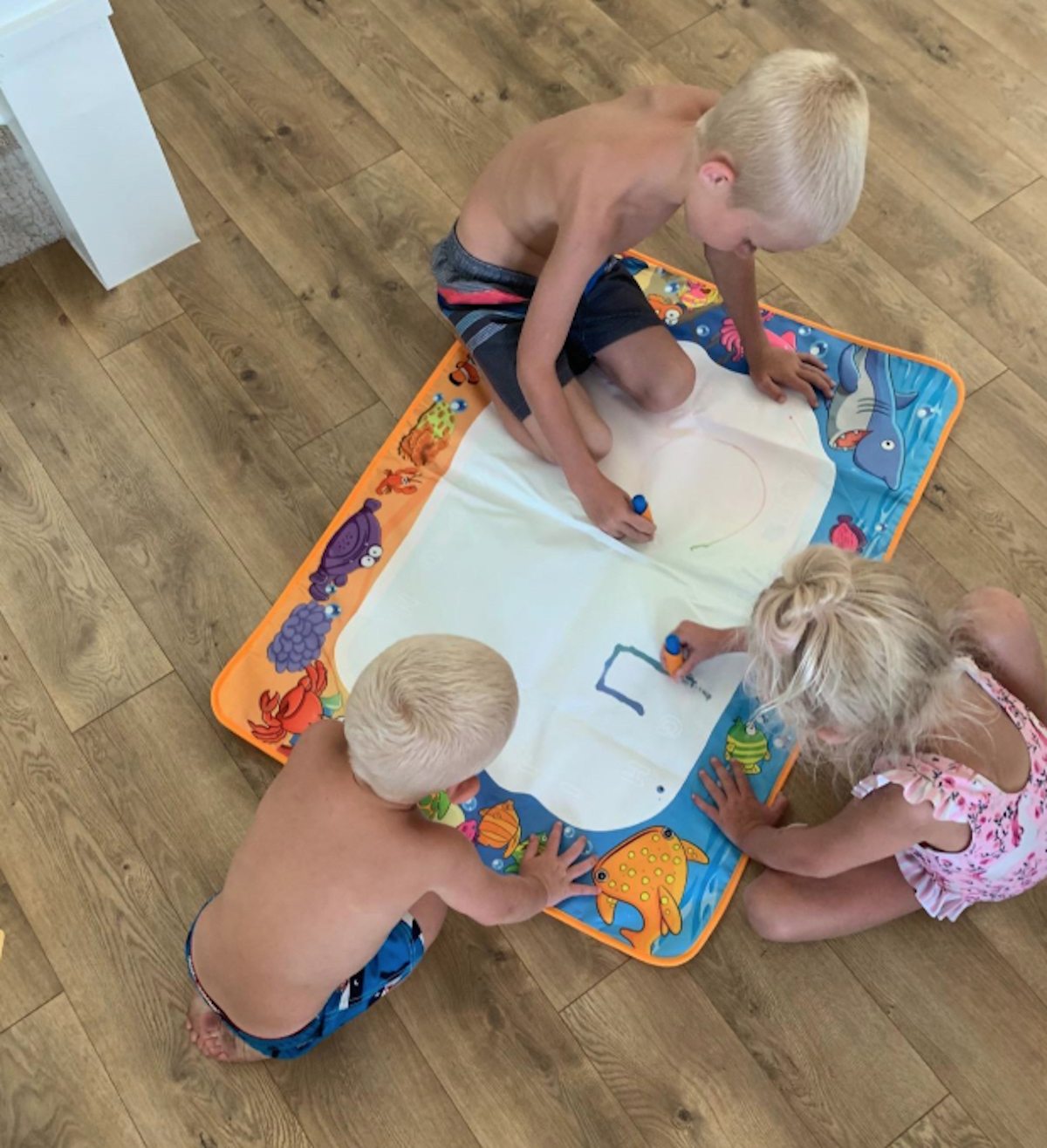 kids drawing on aquadoodle on mat on floor