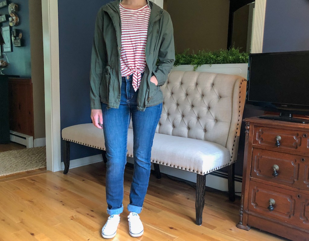 person wearing army jacket stripe shirt and jeans