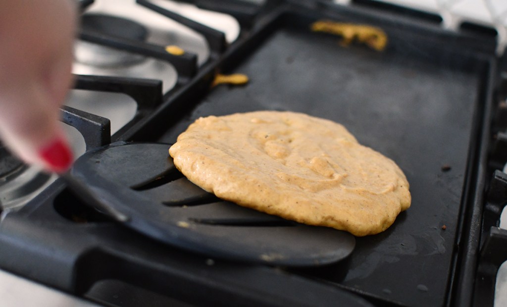 spatula flipping pumpkin pancake on griddle