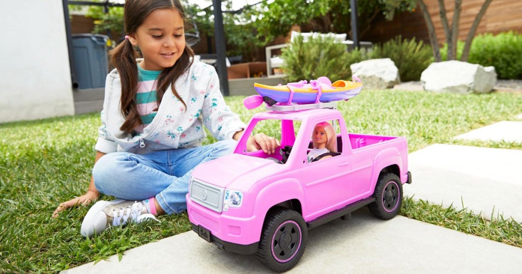 young girl playing with Barbie Kayak Adventure playset outside