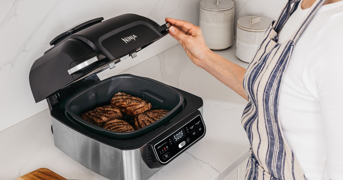 woman standing next to Ninja Foodie 5-in-1 grill 