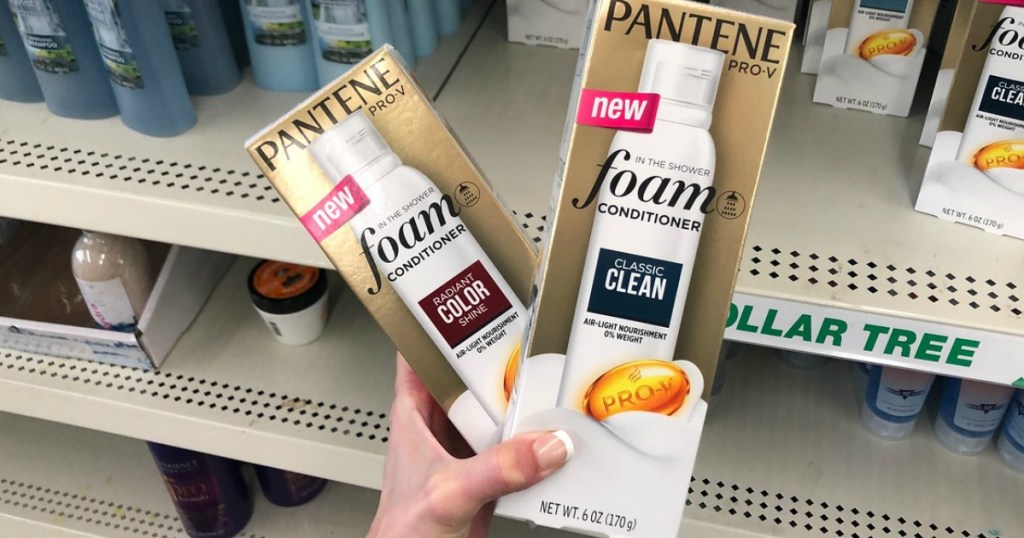 hand holding two packages of hair products by store display