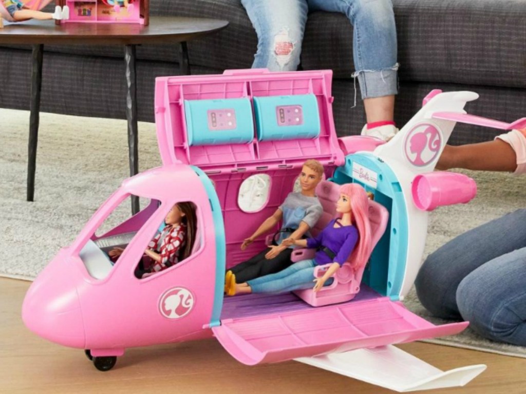 Girls in living room playing with Barbies and Barbie playsets