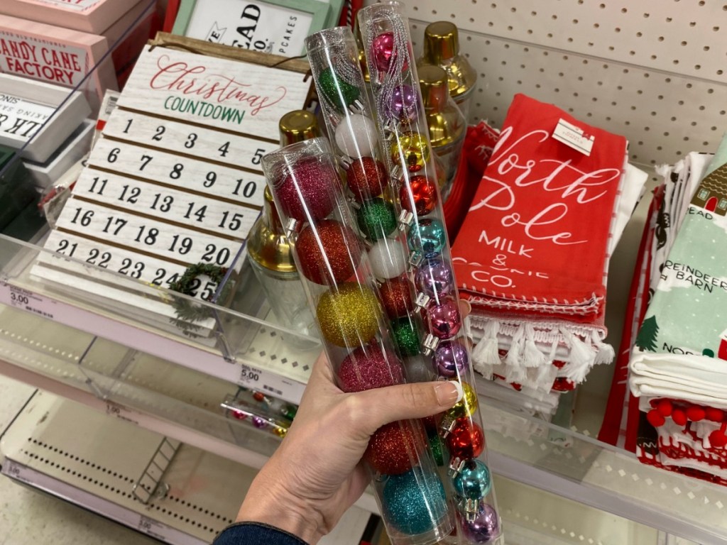 Hand holding several tubes of Christmas tree ornaments