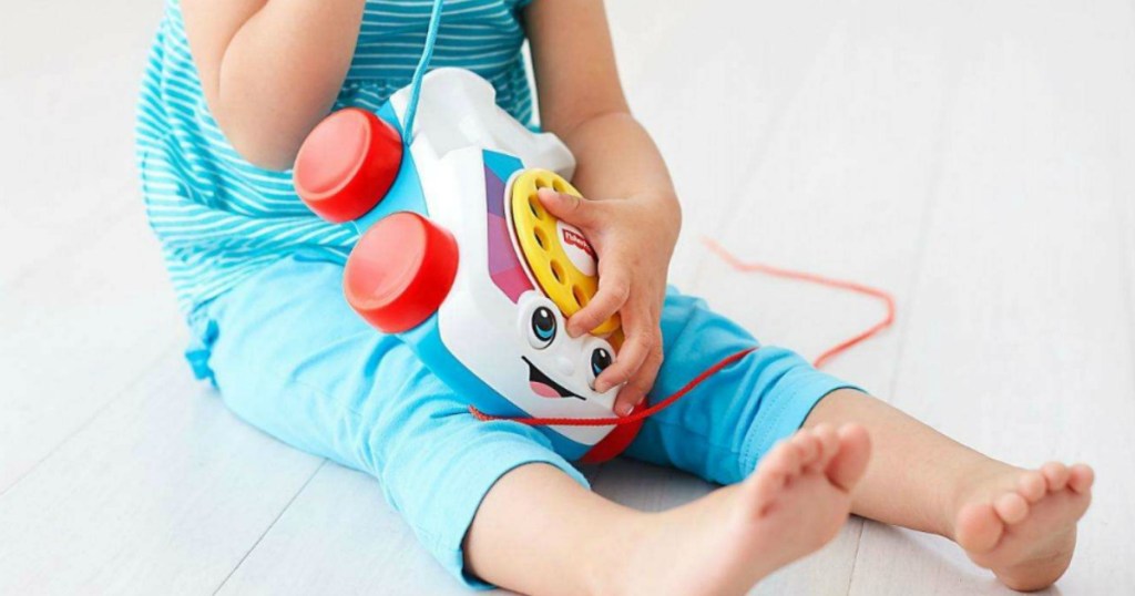 little girl on floor playing with Fisher-Price Chatter Telephone