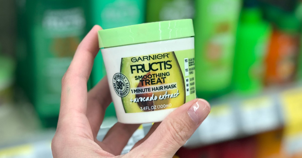 hand holding up a Garnier Hair Mask cup in front of a store shelf