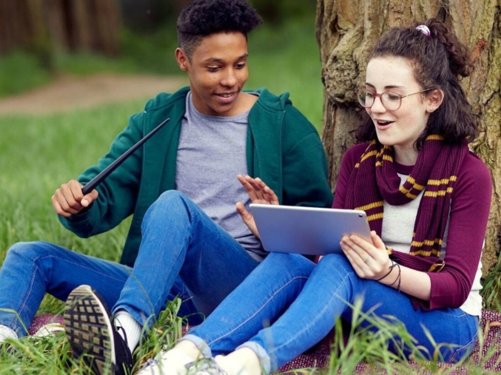 Two teens using the Harry Potter Coding program outside on a tablet with the wand