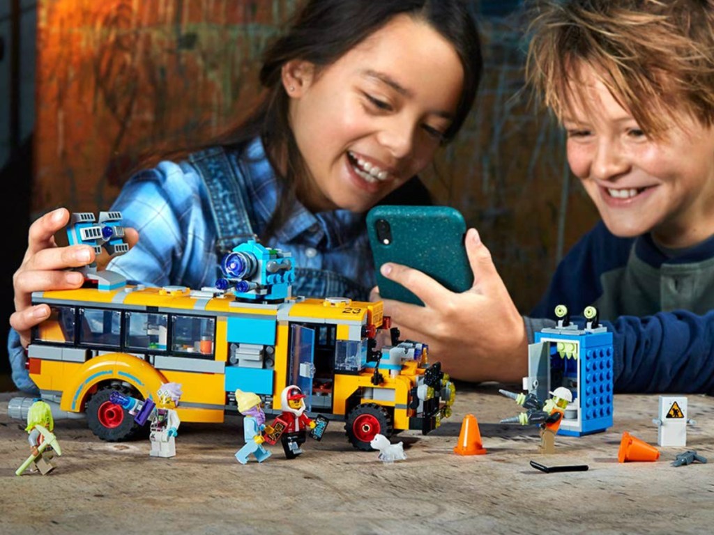 Boy & girl playing with a LEGO Hidden Side Bus set with a phone