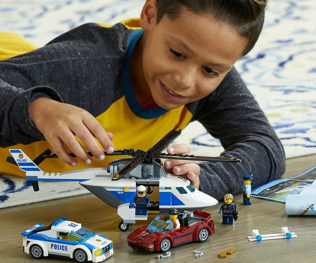 boy playing with a LEGO city set on the floor