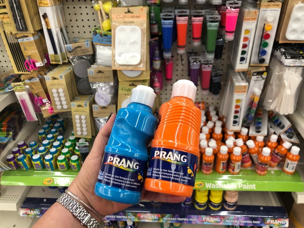 Woman holding Prang Paint bottles in Dollar Tree