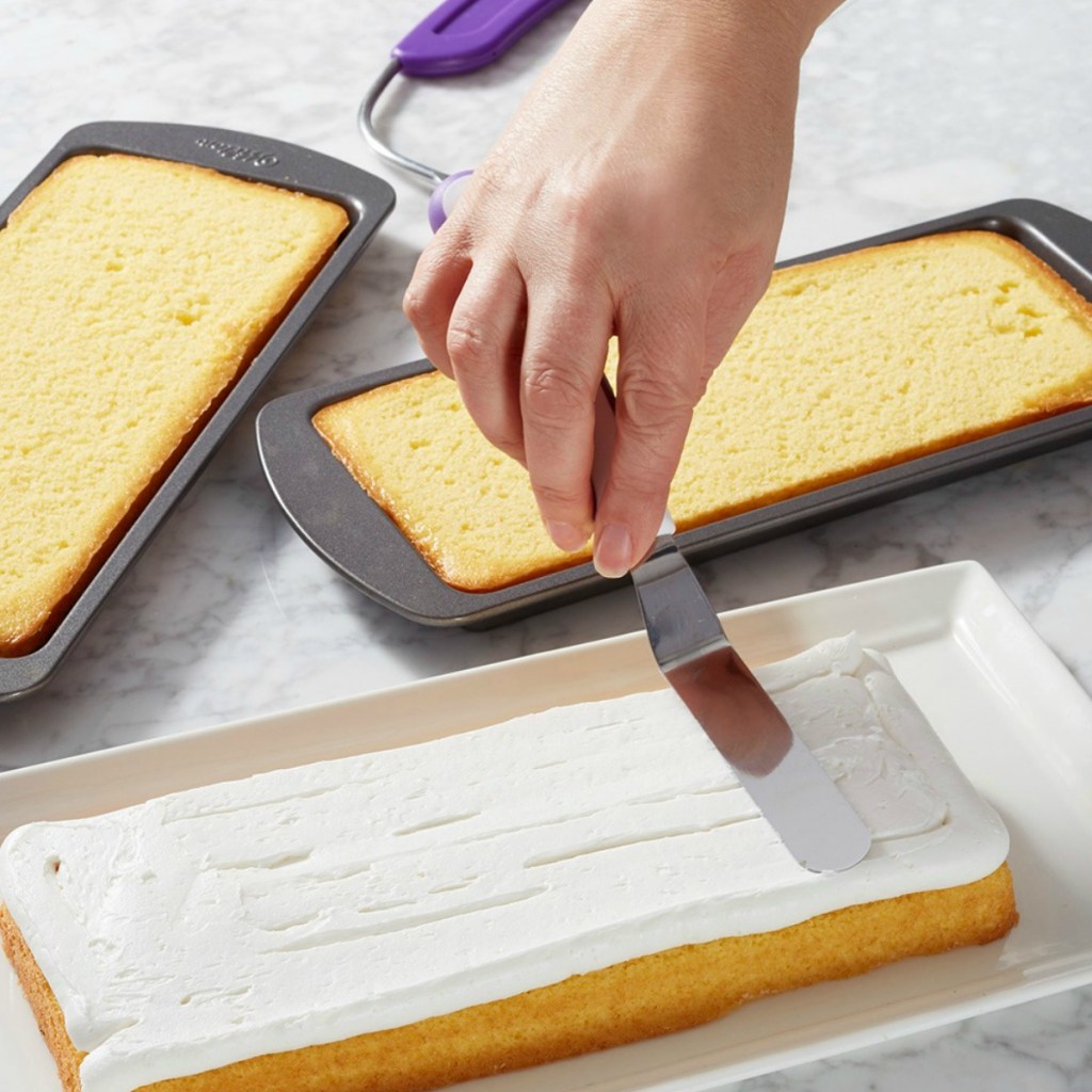 Woman frosting layer of sheet cake