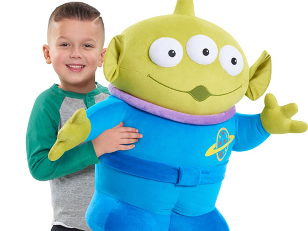 little boy holding a gigantic plush of toy story 4 alien