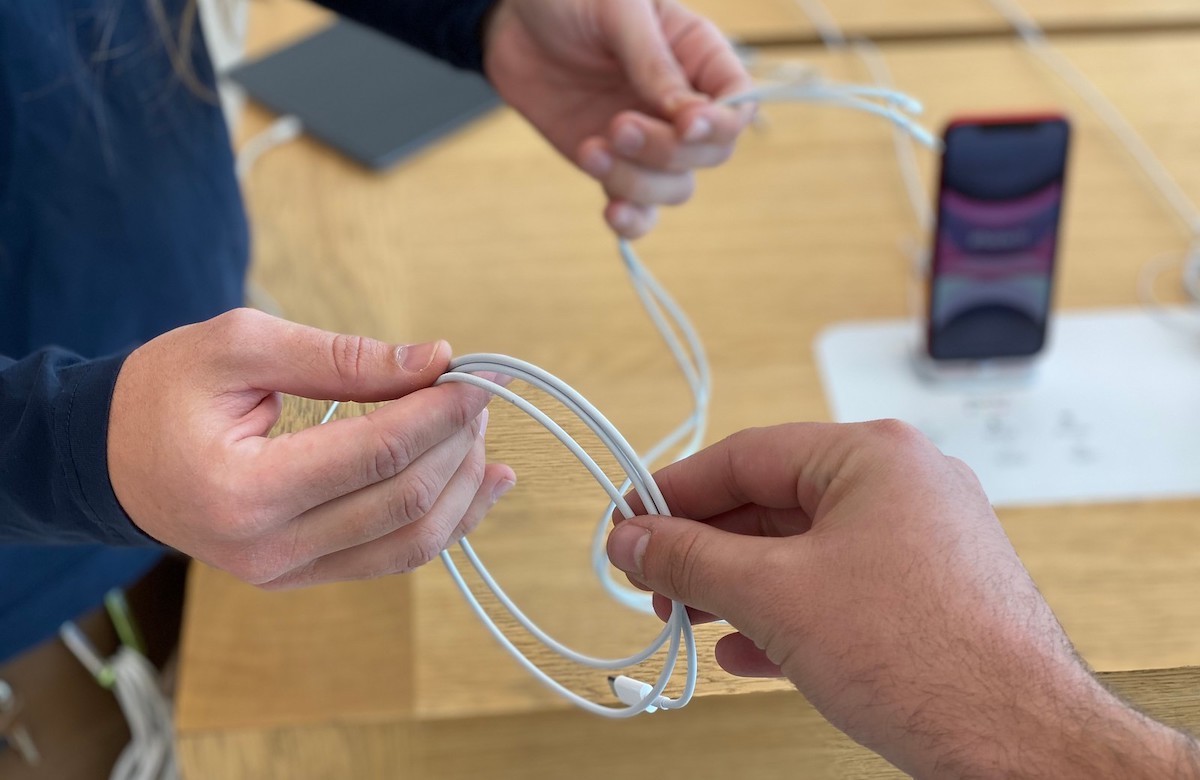 people holding white iphone chargers in hands