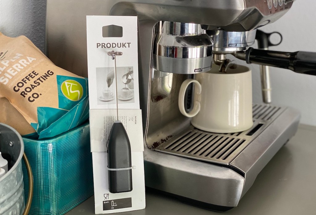 IKEA milk frother sitting next to coffee machine with mug