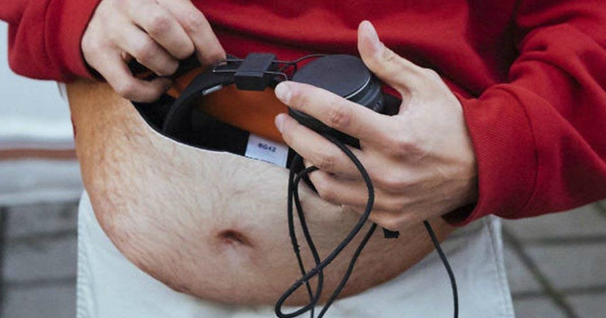 man getting headphones out of fake belly fanny pack 