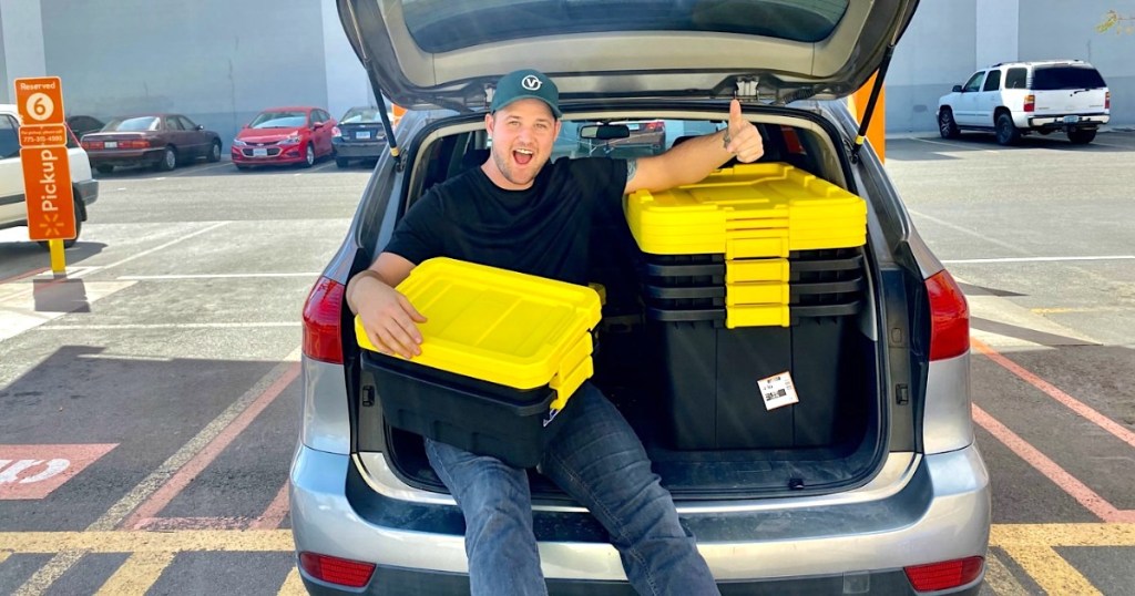 man in the back of car with yellow storage totes